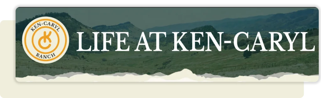Ken-Caryl Ranch newsletter banner featuring the circular ranch logo and large white text reading “LIFE AT KEN-CARYL” over green foothills, with a torn-paper border along the bottom.